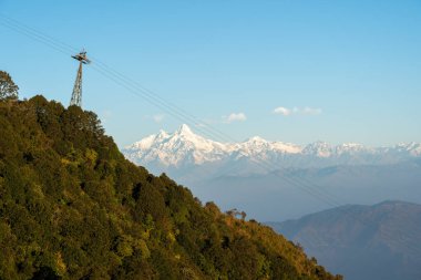 Tepenin kenarında Himalaya Dağları 'nın arka planında bir teleferik kulesi..