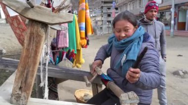 20 Kasım 2021 - Muktinath, Nepal: Tibetli bir kadın küçük bir köyde atkıya yün örüyor.