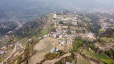 Nepal 'in etrafını saran teraslı tarlalarla bir tepenin yamacına dağılmış bir köyün havadan görüntüsü..