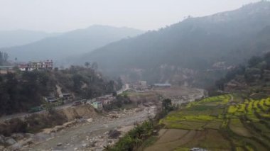 Parlak sarı hardal tarlasının üzerinde uçuyor, bir nehir ve kırsal Nepal 'de otoyol boyunca küçük bir kasaba..