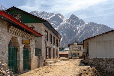 Lukla, Nepal - 7 Mart 2022: Arka planda dağlar olan küçük Lukla kasabasında bir toprak sokak.