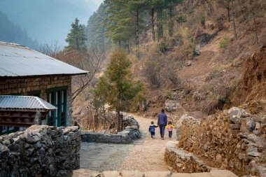 Lukla, Nepal - 10 Mart 2022: İki çocuğuyla birlikte Himalaya Dağları 'ndaki bir patikada eve yürüyen bir baba.