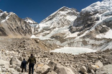 Bazı yürüyüşçüler Khumbu buzulundaki kayaların üzerinden Everest Ana Kampı 'na doğru yürüyorlar..