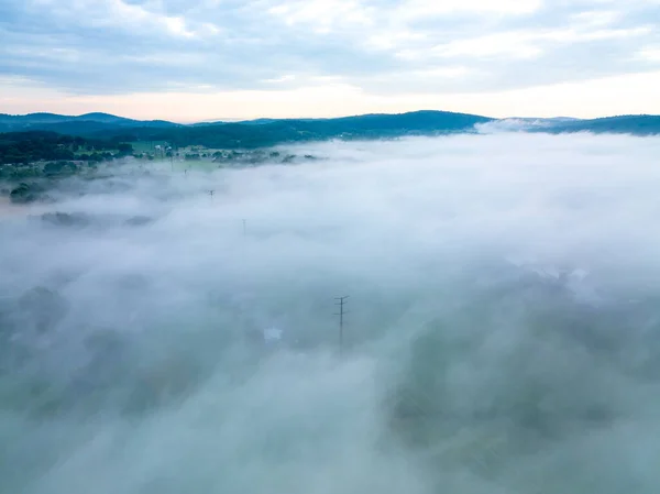 Uma Vista Aérea Cima Nevoeiro Enquanto Cobre Paisagem Campos Fazendas — Fotografia de Stock