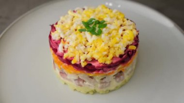 Kürk mantonun altında ringa salatası. Ringa, pancar, patates, havuç ve yumurtadan geleneksel Rus çoklu salatası. Yakın plan, gri arkaplan, döndürme.