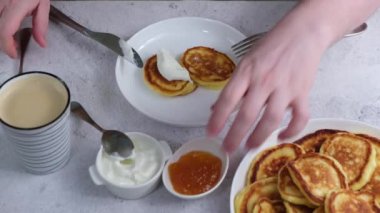 Adam şuruplu ya da süzme peynirli krep yiyor. Ekşi krema ve reçelli. Geleneksel Rus ve Ukrayna mutfağı yemeği. Sağlıklı ve lezzetli bir kahvaltı veya tatlı. Yakın plan..