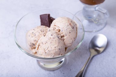 Kâsede çikolata parçacıklı ev yapımı dondurma. Üç top dondurma ve bir fincan kahve. Yakın plan..