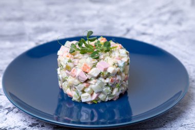 Mavi tabakta bezelye filizleriyle süslenmiş Olivier salatası. Geleneksel Yeni Yıl ve Noel Rus salatası. Yakın çekim, seçici odaklanma.