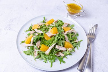 Tavuklu salata, portakal ve roka. Zeytinyağı ve tahıllı hardal karışımı. Yakın plan..