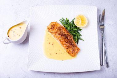 Beurre blanc soslu somon, ıspanak ve limon. Pırasalarla süslenmiş. Geleneksel Fransız yemeği. Yakın plan..