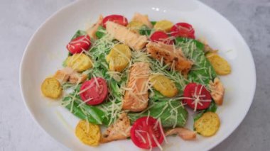 Kırmızı balıklı Sezar salatası (somon, alabalık), kirazlı domates, kızarmış ekmek, parmesan peyniri ve romaine. Geleneksel Amerikan yemeği. Yakın çekim, seçici odaklanma.