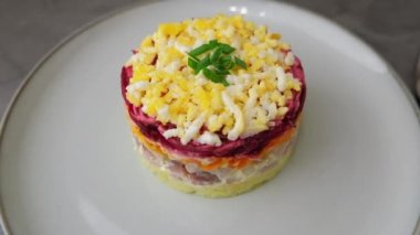 Kürk mantonun altında ringa salatası. Ringa, pancar, patates, havuç ve yumurtadan geleneksel Rus çoklu salatası. Yakın plan, gri arkaplan, yavaş çekim.