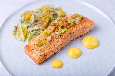 Rezeneli kızarmış somon ve Hollandez soslu portakal salatası. Pırasalarla süslenmiş. Fransız yemeği. Yakın plan..