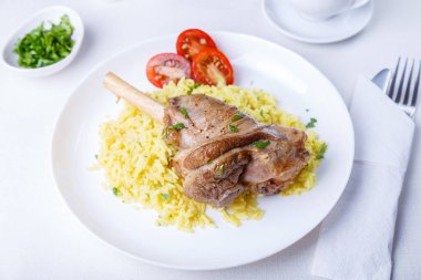 Pirinçli kuzu incik, maydanoz, domates ve beyaz tabakta sos. Geleneksel yemek. Yakın çekim, seçici odaklanma.