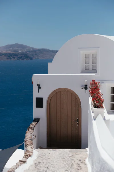 Oia City, Santorini Adası, Yunanistan ve Avrupa 'daki Yunan mimari otelinin beyaz cephesine açılan güzel kahverengi kapı. Santorini adasının güzel detayları. Deniz manzaralı ünlü seyahat yeri