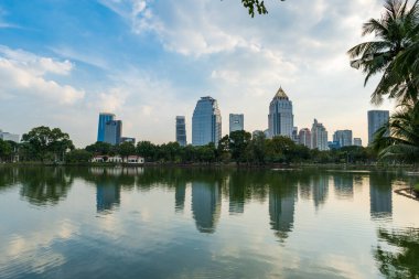 Bangkok 'taki Lumpini parkı ve Bangkok şehir merkezindeki ufuk çizgisi. Lumphini Parkı yerel halk ve turistler için popüler bir parktır..