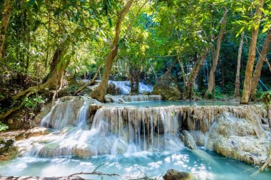 Tayland 'daki Erawan Ulusal Parkı. Erawan Şelalesi popüler bir turistik yerdir ve zümrüt mavisi suyuyla ünlüdür. Tropikal iklimde fantezi atmosferi olan derin orman.