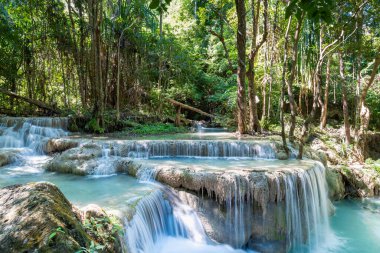 Tayland 'daki Erawan Ulusal Parkı. Erawan Şelalesi popüler bir turistik yerdir ve zümrüt mavisi suyuyla ünlüdür. Tropikal iklimde fantezi atmosferi olan derin orman.