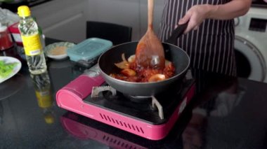 Ev hanımı evdeki tavada ev yapımı kızarmış Kore Kochujang domuz eti pişiriyor..