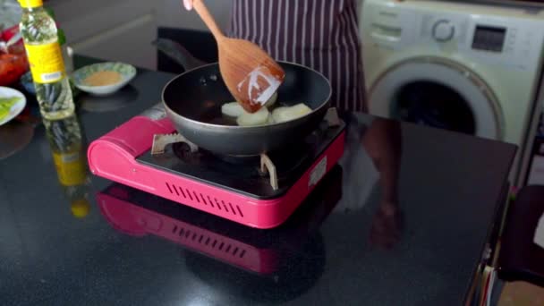 女性は家でホットパンに油で白玉ねぎを調理しています — ストック動画