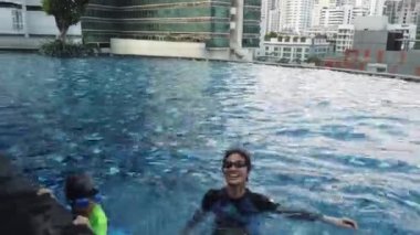 Anne iki çocuğa yüzme havuzunda yüzmeyi öğretiyor..