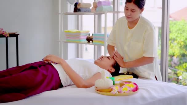 アジアの女性は 女性セラピストからタイリラックススパでヘッドマッサージを受けています — ストック動画