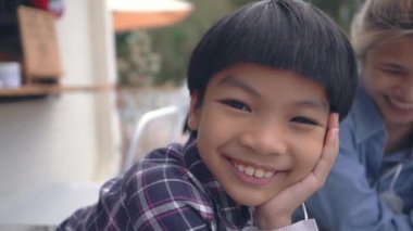 Tatlı Asyalı çocuk kameraya cilveli bir ifadeyle gülümsüyor..