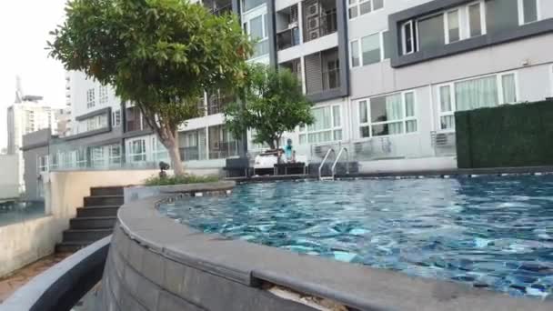 小さな男の子が水泳プールを飛び降りますマンションのスイミングプールで泡 — ストック動画