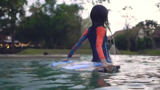 アジアの女の子は熱帯リゾートスイミングプールで小さな泡板で遊んでいます — ストック動画