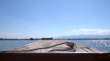 Arkasında dağ ve bulutlu gökyüzü olan büyük bir gölü gezen ahşap bir tekneden manzara.