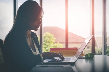 Sadece dizüstü bilgisayarda çalışan Asyalı kadın. Siluet güneş ışığı tonu..