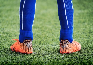 Kid footballer feet closed up on a green grass field for youth soccer training concept.