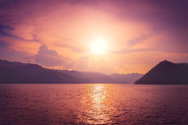 Siluet Adası dağının açık sularında mor gün batımı gökyüzü yansıması.
