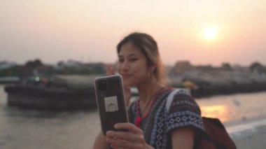 Kadın turist, Chao Phraya Nehri ve Temple in the Background, Bangkok, Tayland ile selfie çekiyor..