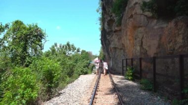 Turist Ailesi, Tayland, Kanchanaburi 'deki Death Railway yolunda yürüyor..