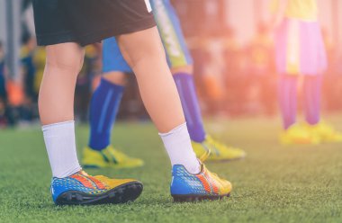 Kid footballer feet closed up on a green grass field for youth soccer training concept.