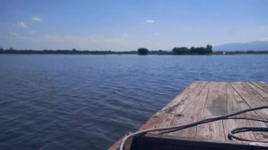 Tahta gemi başı durgun bir gölde ağır çekimde yüzüyor.