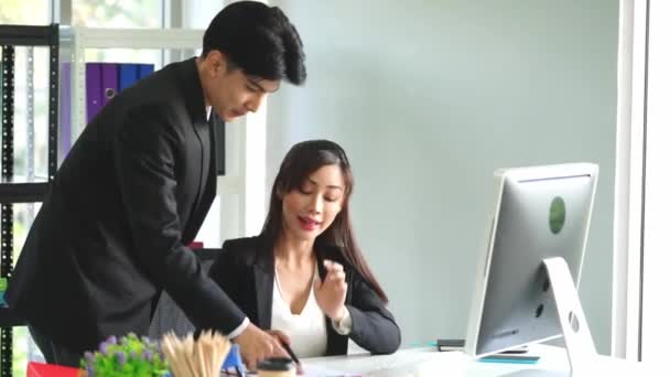 在电脑前 亚洲办公室的工作人员正在愉快而微笑地谈论工作问题 — 图库视频影像