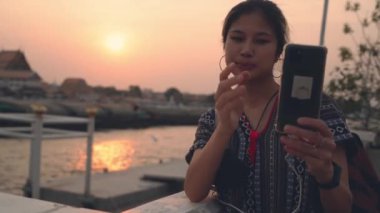 Thai Traveler is taking selfie photo using Mobile phone in Chaopraya River, Bangkok, Thailand.