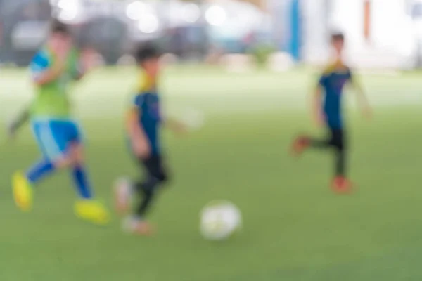 Blurred kid soccer match in indoor artificial field.