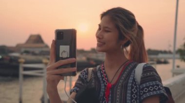 Beautiful Asian woman traveller is taking selfie photo with Bangkok river in the Background.