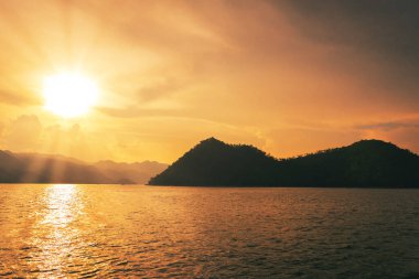 Siluet Adası dağının açık sularında altın günbatımı gökyüzü yansıması.