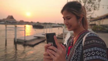 Beautiful Asian woman traveller is taking selfie photo with Bangkok river in the background