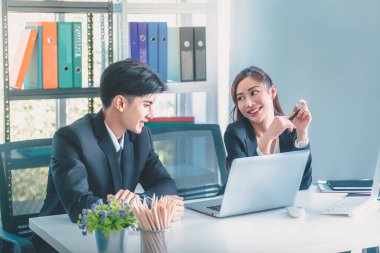 Asian office worker having a flirty conversation talk while working together with smile and laughing.