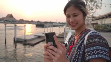 Asian Female Tourist is taking selfie in Chaopraya river in Bangkok, Thailand.