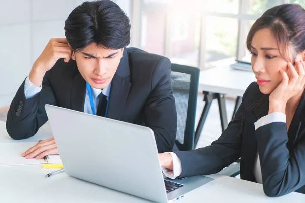 Two disappointed Business person is looking at computer screen with upset and tired faces for business failure concept.