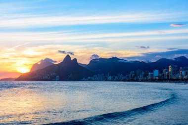 Ipanema sahilindeki Rio de Janeiro şehrinin arkasında gün batımı