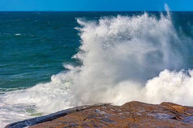 Brezilya 'nın Rio de Janeiro şehrinde dalgalı bir deniz gününde kayaların üzerinden süzülen mavi gökyüzü.