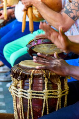 Percussionist playing a rustic and rudimentary percursion instrument atabaque during afro-brazilian cultural manifestatio clipart