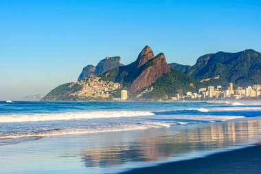 Rio de Janeiro şehrinde şafak vakti. Islak kumdaki binaların yansımasıyla boş Ipanema plajı.